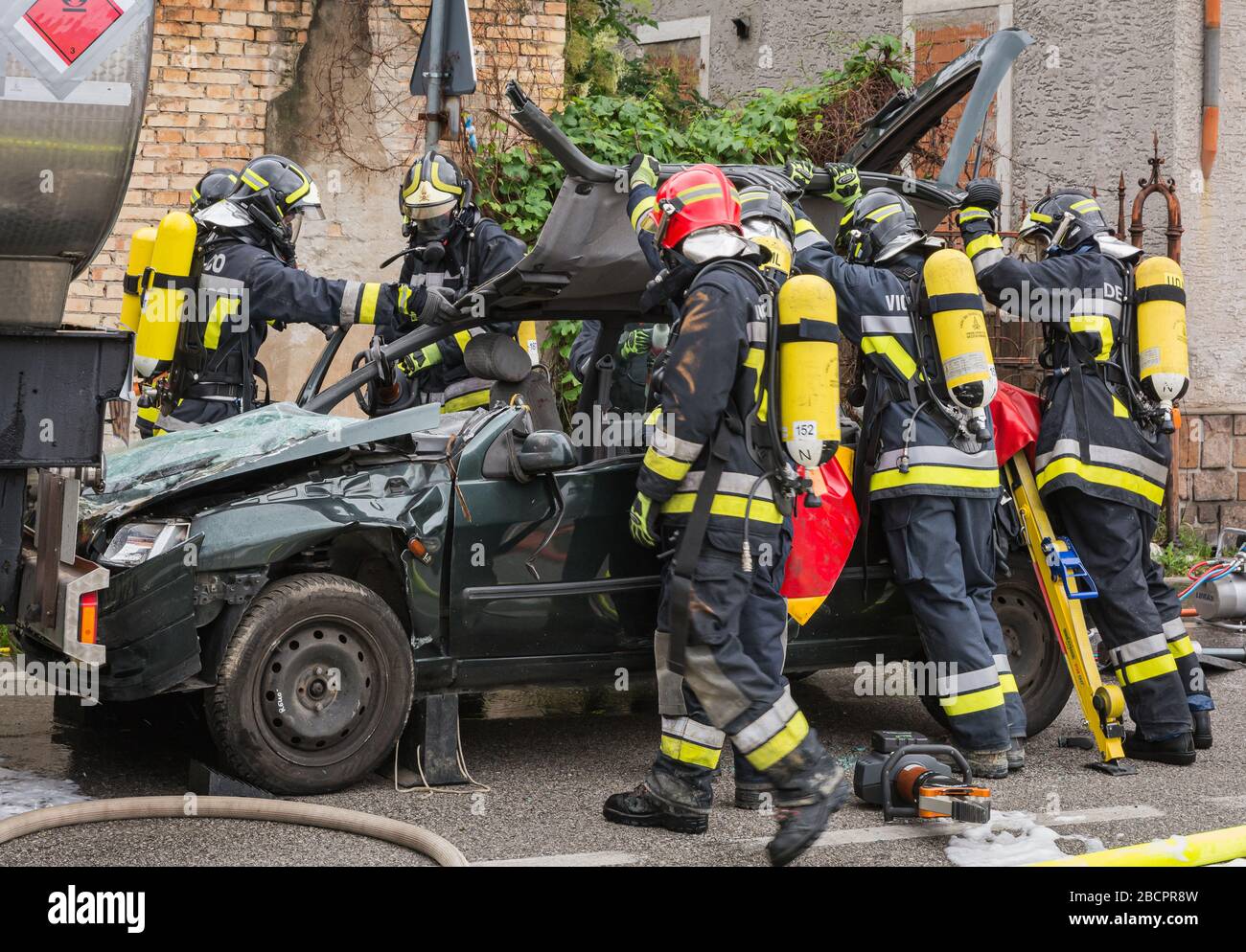 firefighters crewss rescue trapped driver during a road accident simulation with cars, train and trucks. firefighters with Breathing Apparatus and Hyd Stock Photo