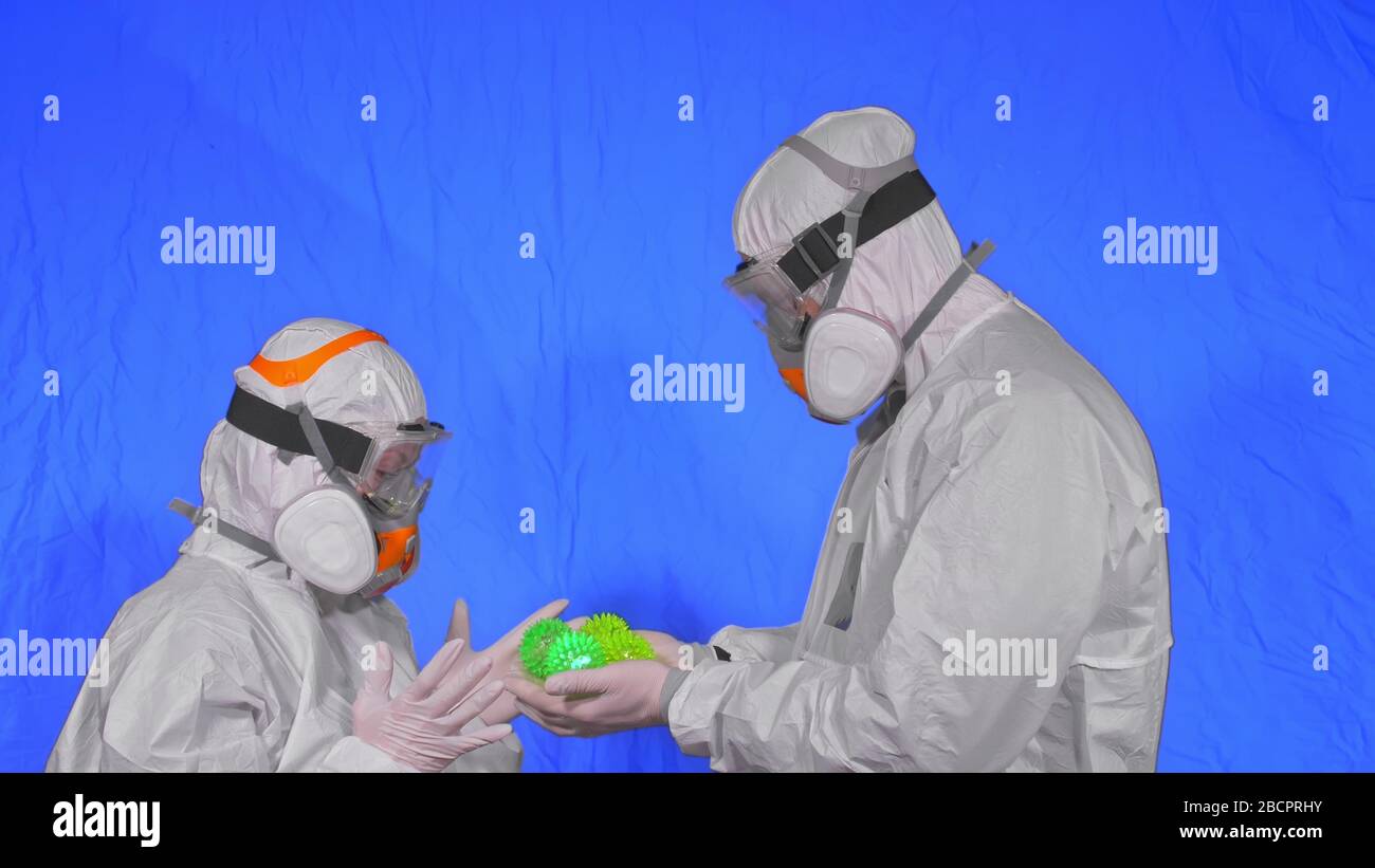 Doctor in respirator show a virus model. Slow motion. Woman wearing protect medical aerosol spray paint mask. Green ball spike thorn. Stock Photo