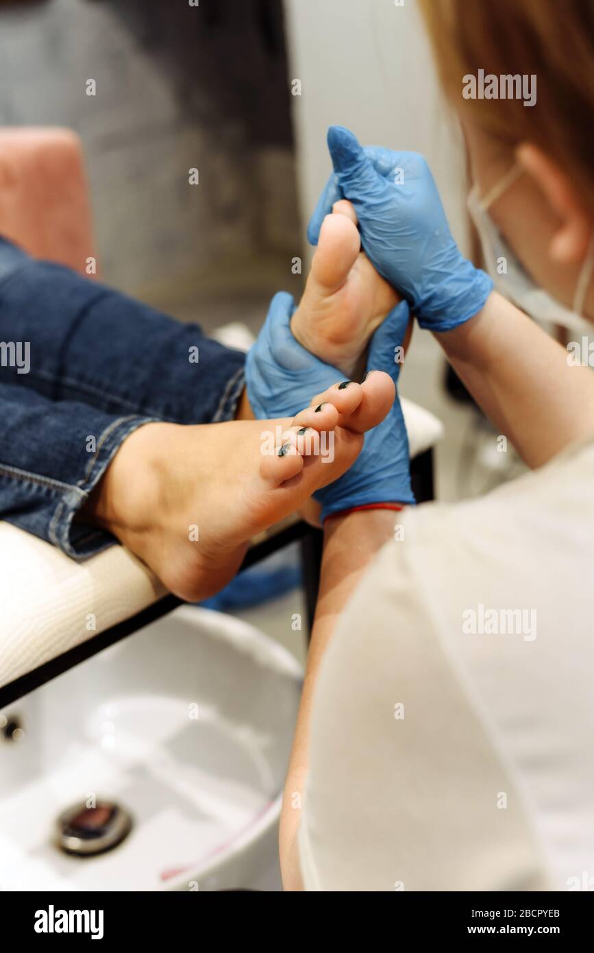 A pedicure master does a foot massage and prepares nails for a pedicure