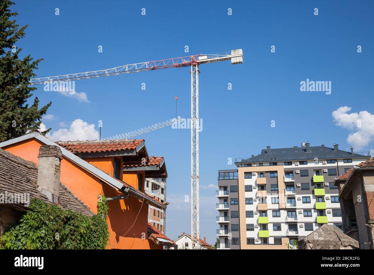 Peri urban scenery of the suburb of Belgrade, with cranes on a construction site with modern housing buildings being built and old houses ready for de Stock Photo