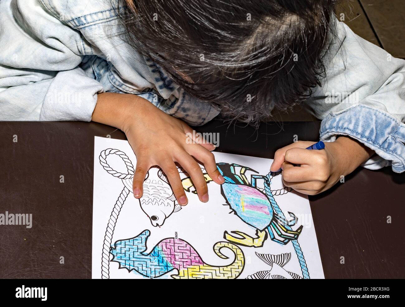 Pretty asian child left handed while doing a coloring activity with