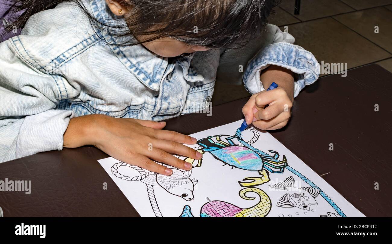 Pretty asian child left handed while doing a coloring activity with