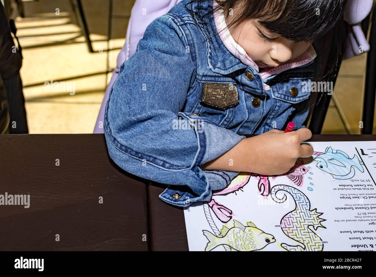 Pretty asian child right handed while doing a coloring activity with