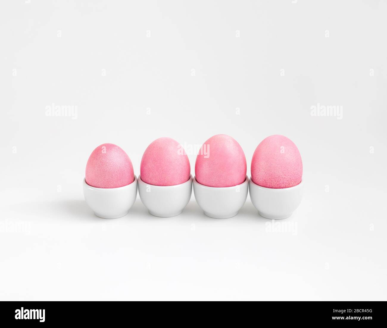 Easter composition with pink eggs in stands on a white background. Minimal Easter concept. Copy space. Stock Photo