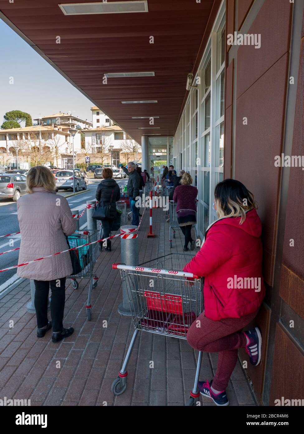 Florence, Italy - 2020, April 4: European consumers in line at the supermarket for grocery shopping, during Corona Virus pandemic emergency. Stock Photo