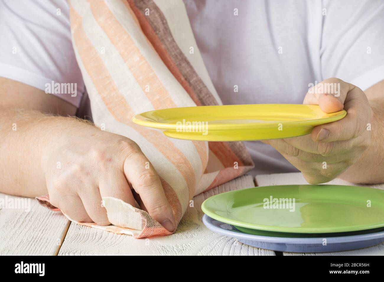 Close up mans hand wipe with towel a clean plate after washing all the