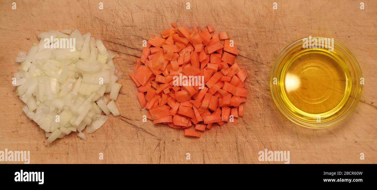 Sliced onions, carrots and olive oil on a cutting board. Top view. Stock Photo