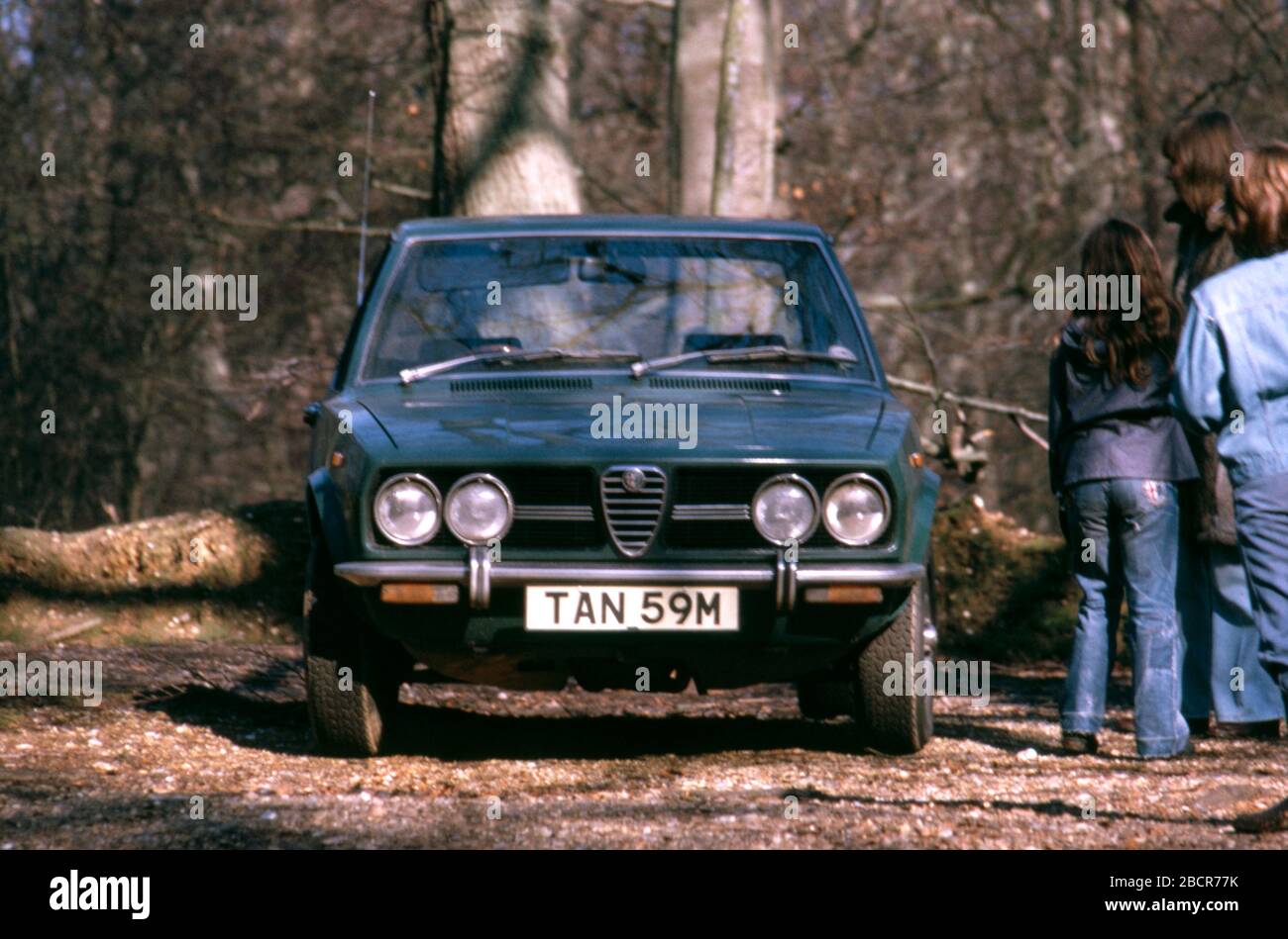 A mother and her two kids standing next to their green Alfa Romeo Alfetta parked in a wood UK 1974 Stock Photo