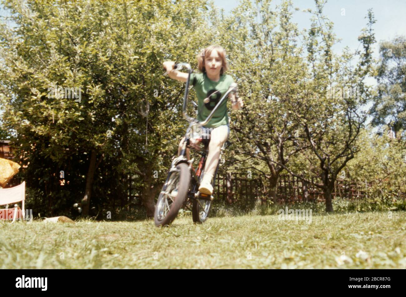 A boy riding his Raleigh Chopper bike in the back garden of his family home in 1973 in the suburbs of London UK. Stock Photo