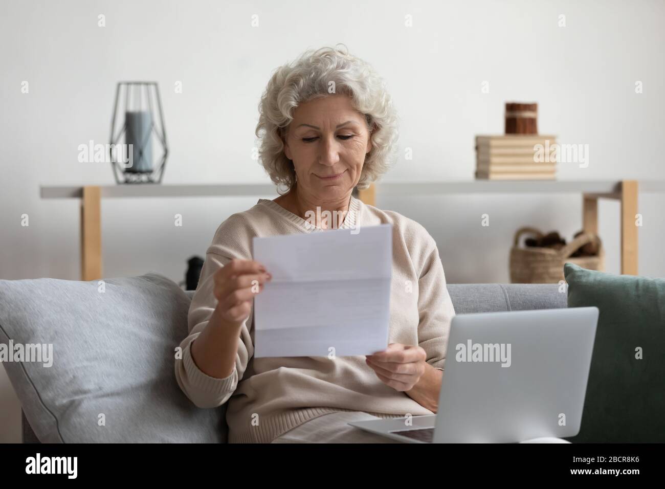 Pleasant smiling elderly mature woman reading banking loan paper notification Stock Photo Alamy