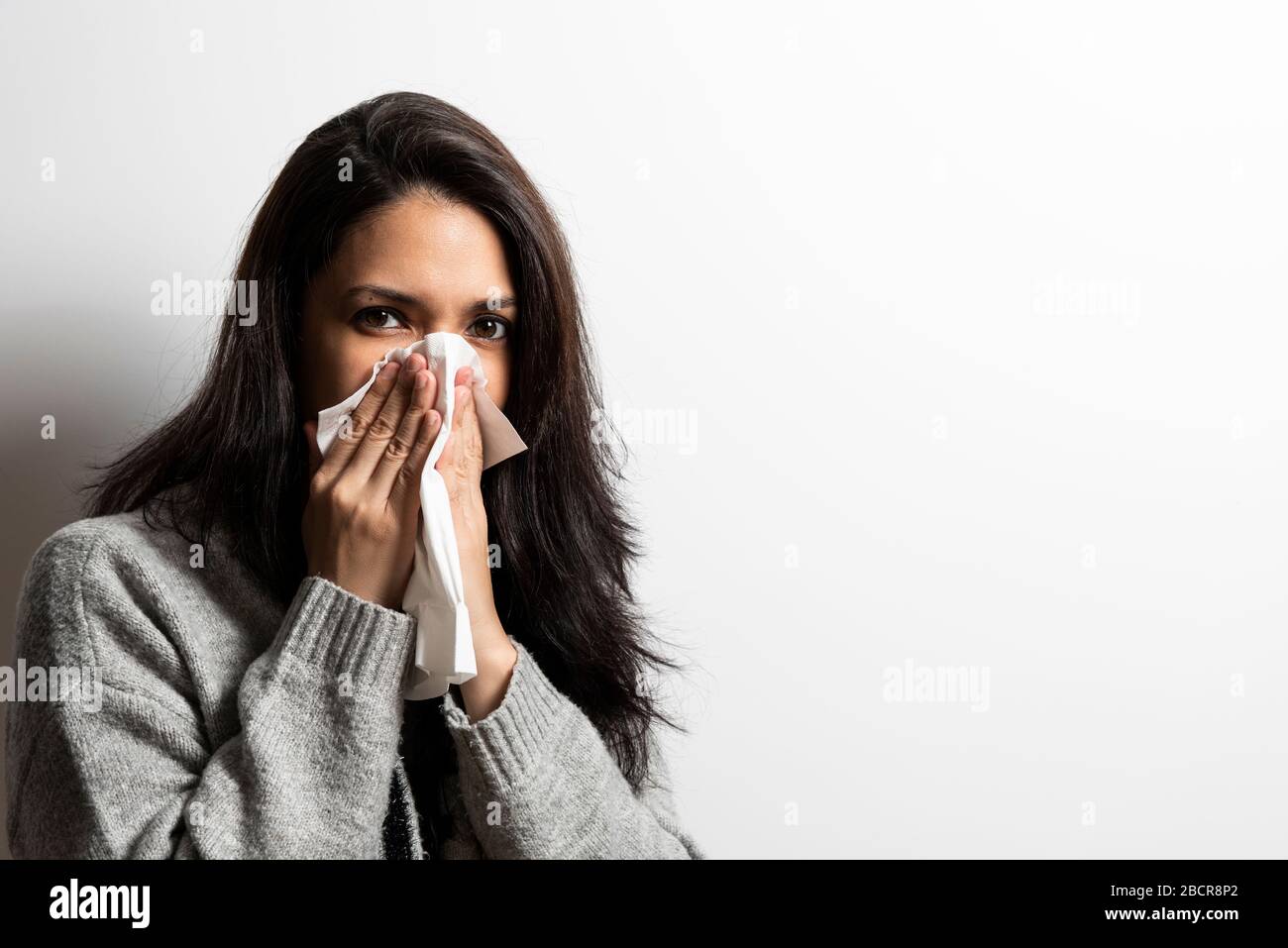 young woman blowing her nose on a white background. Stock Photo