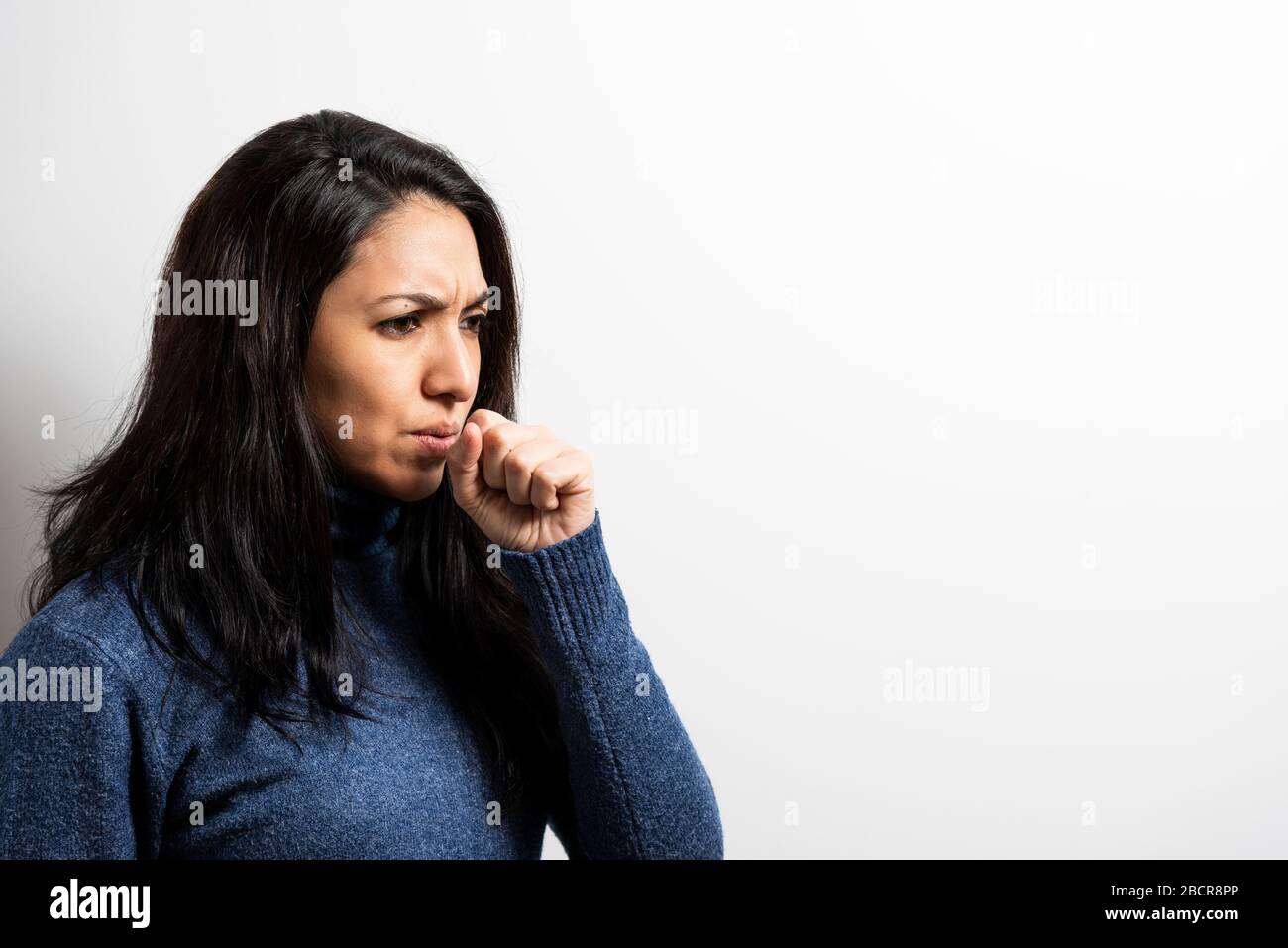 young woman coughing on a white background. Stock Photo