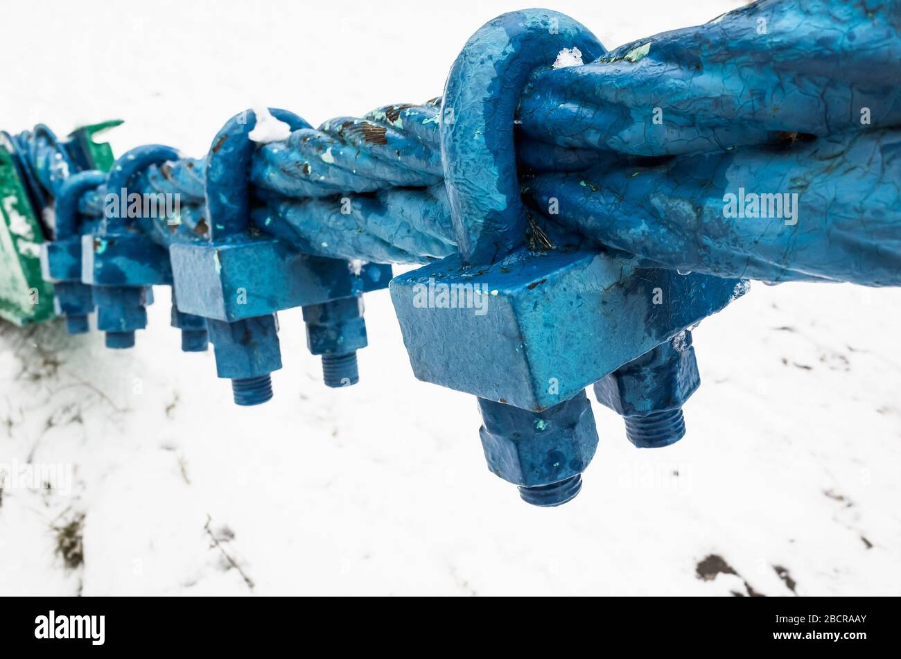 Blue painted steel rope with end fixing locks, macro photo with selective focus Stock Photo