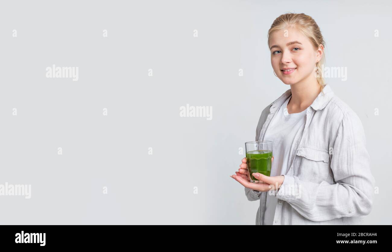 Girl drinking fresh raw green detox vegetable juice on gray Stock Photo