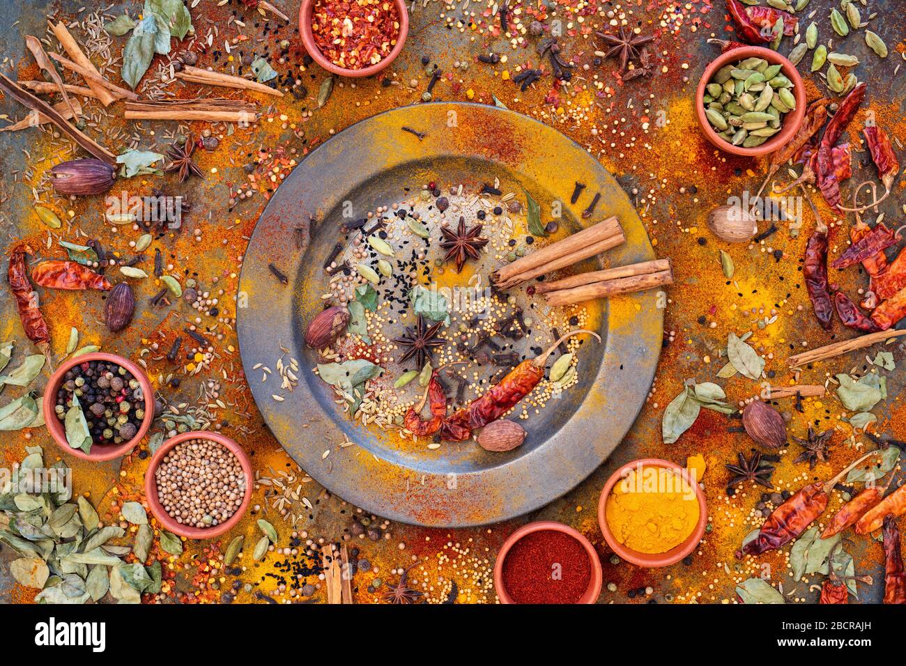 Aromatic spices on and around a pewter plate on slate background Stock Photo