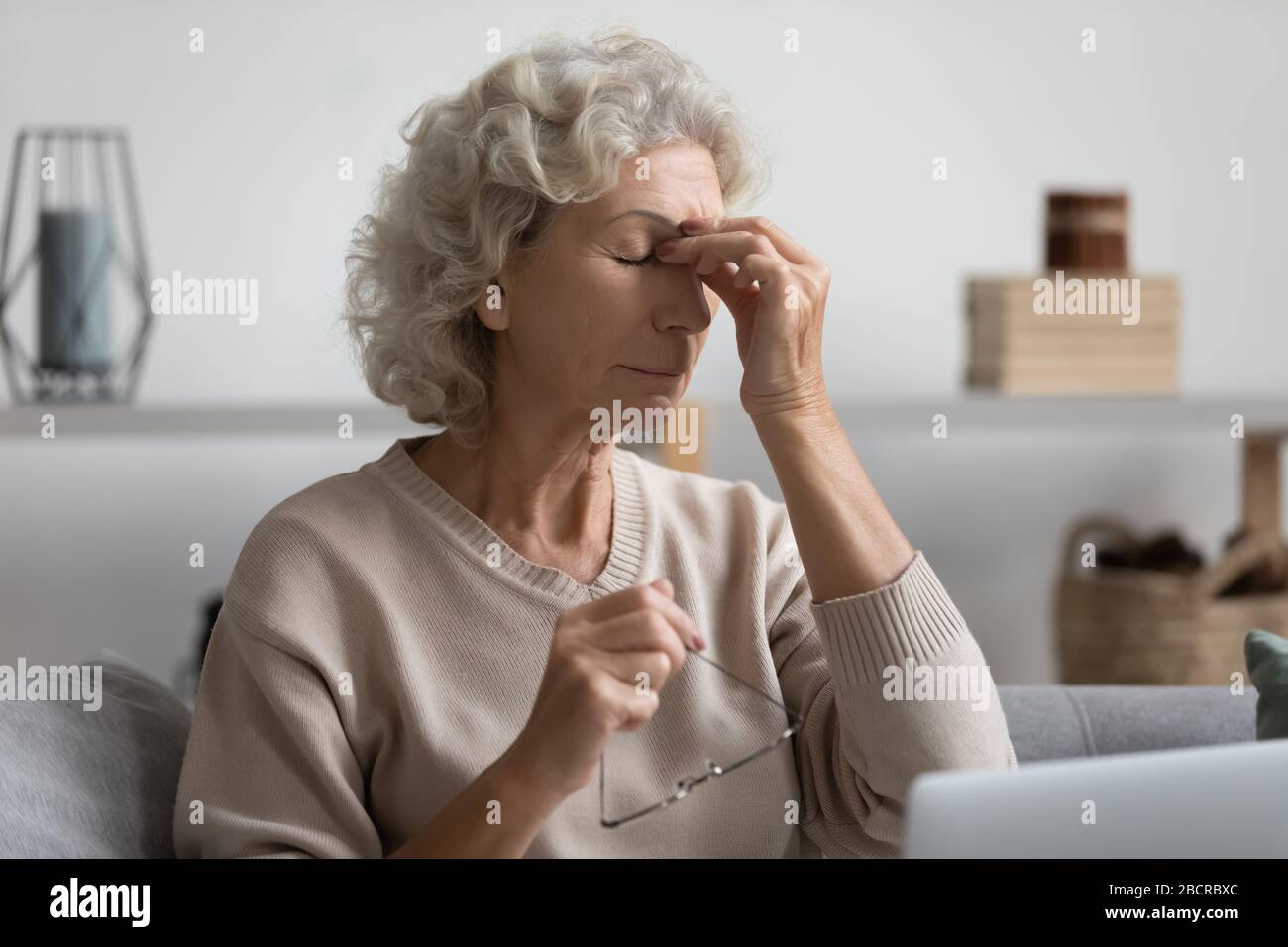 Middle aged grandmother rubbing eye, feeling tired. Stock Photo
