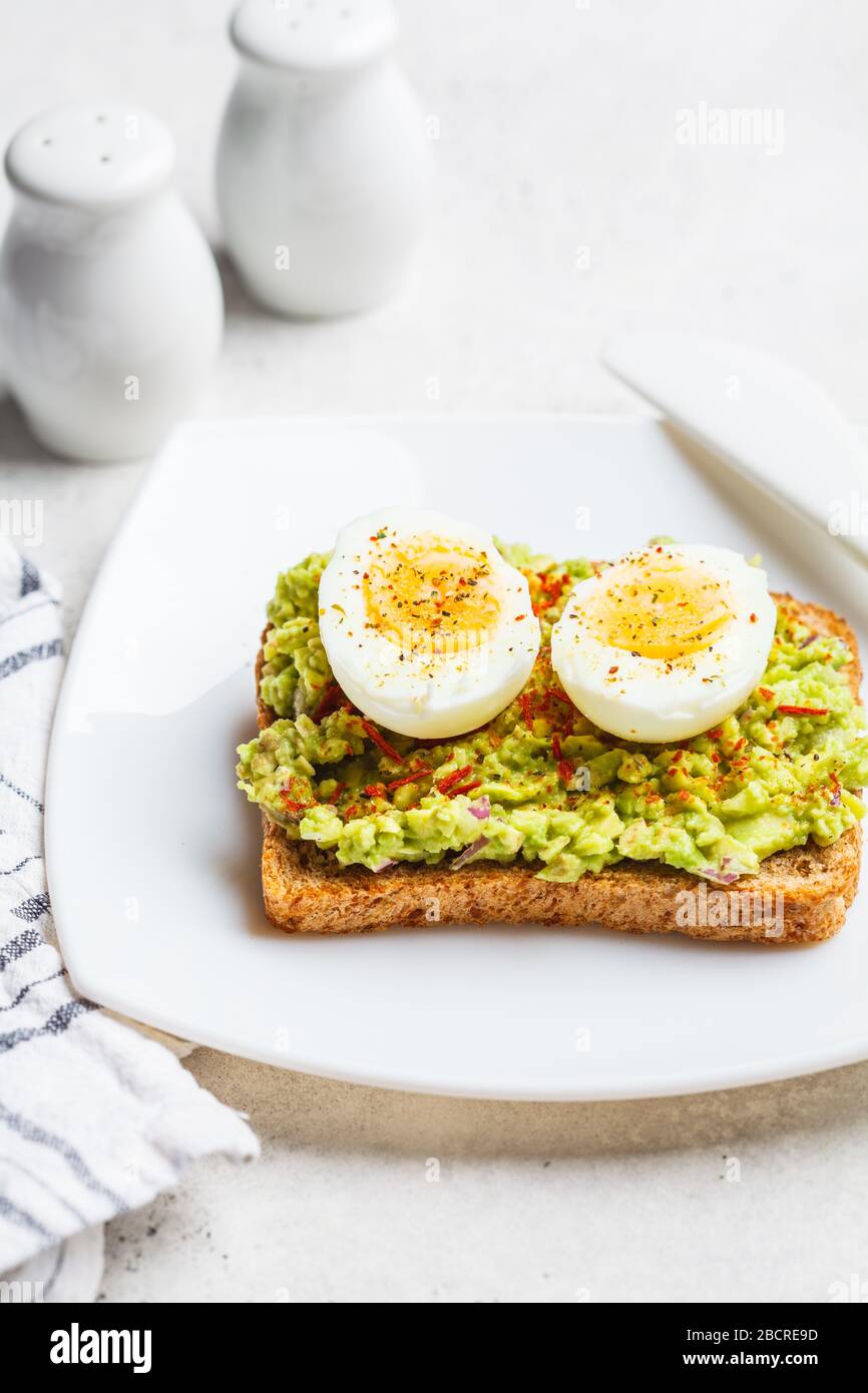 Breakfast avocado toast with egg on a white plate, white background