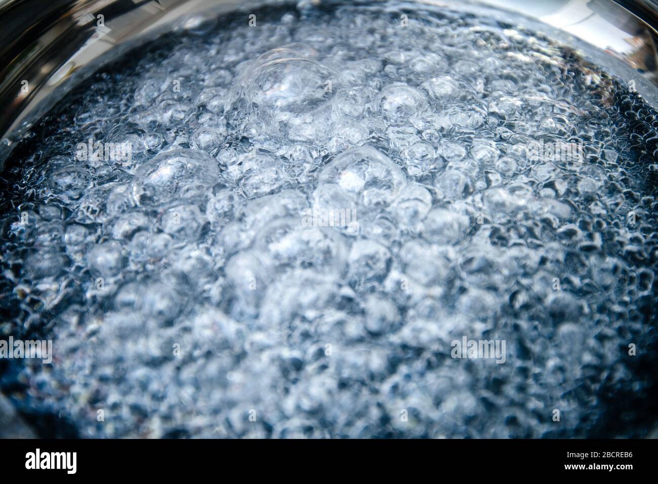 Closeup macro shot of boiling water inside new frying stainless steel