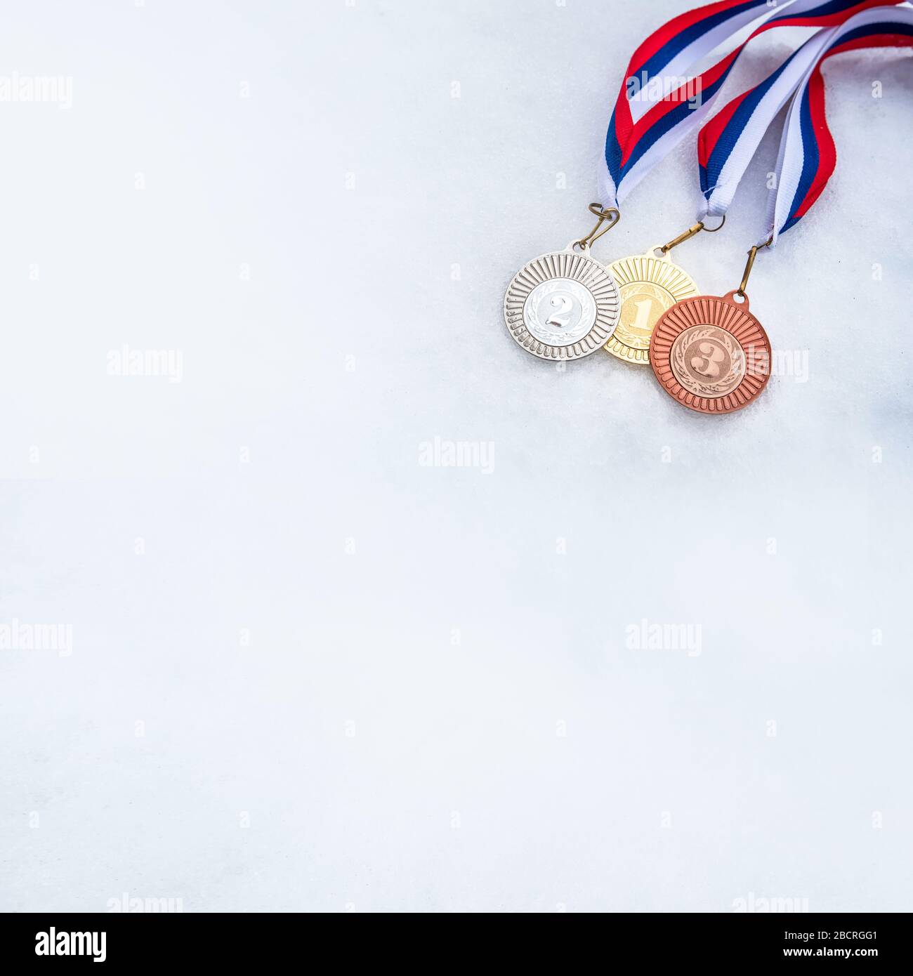 Gold silver and bronze sport trophy in snow. Winter game. White edit space. Stock Photo