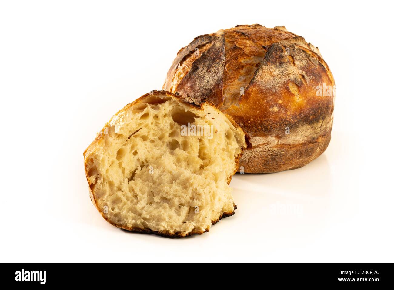 A homemade baked loaf of round artisan white sourdough bread isolated ...