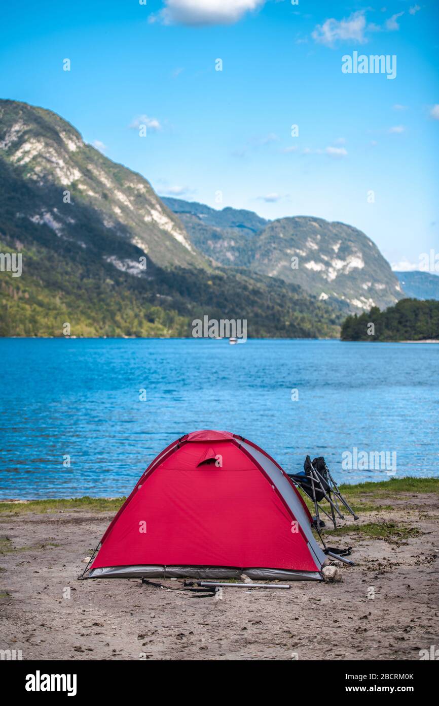 Tent Camping. Modern Tent on the Lake Waterfront. Scenic Slovenian Landscape with Mountains. Vertical Photo. Stock Photo