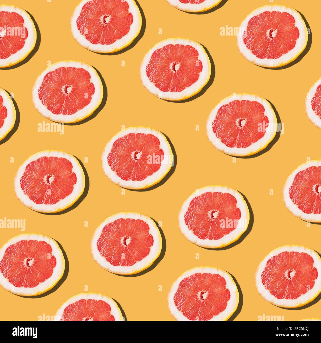 Pink ripe grapefruit slices on the orange background pattern Stock Photo