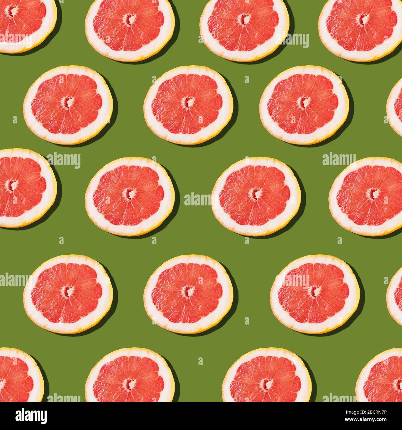 Pink ripe grapefruit slices on the green background pattern Stock Photo