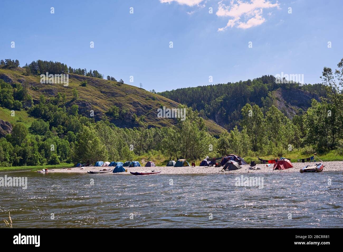 Tourist camp on the background of the river. Tents under the blue sky. Rafting on a mountain river. Stock Photo