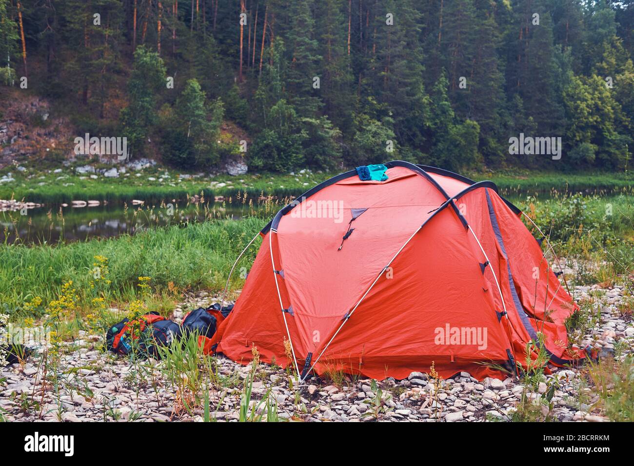 Tourist camp on the background of the river. Tents under the blue sky. Rafting on a mountain river. Stock Photo