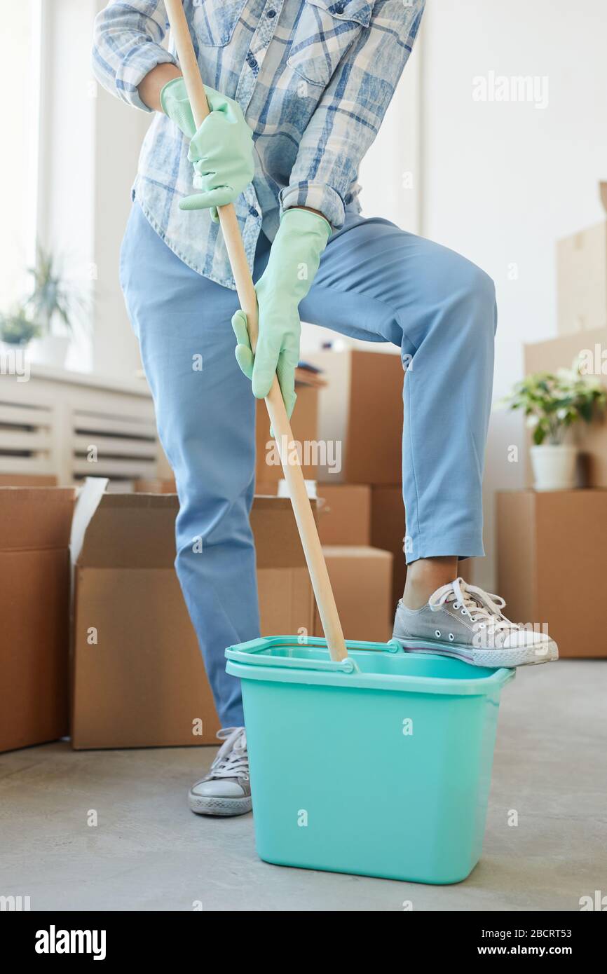 Vertical low section portrait of cheerful young woman cleaning new house or apartment while moving in Stock Photo