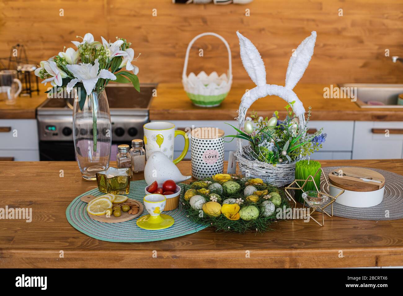 Lemons, olives, almonds on a wooden board, Easter eggs at the back Stock Photo