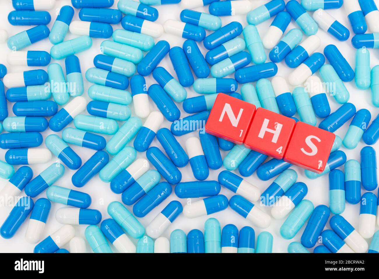 NHS letters tiles & assorted blue pills. Metaphor NHS in Covid 19 pandemic, NHS heroes, NHS prescriptions, UK National Health Service, medicine in UK Stock Photo
