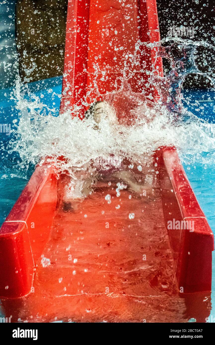 A young girl splashes into water at the bottom of a slide Stock Photo