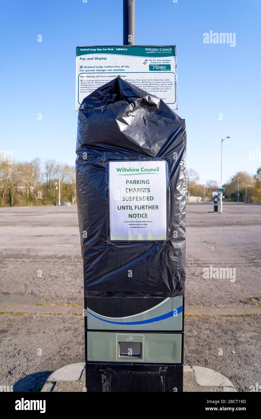 Public car park ticket machine covered with bin bag and a poster advising parking charges suspended during Coronavirus emergency Stock Photo
