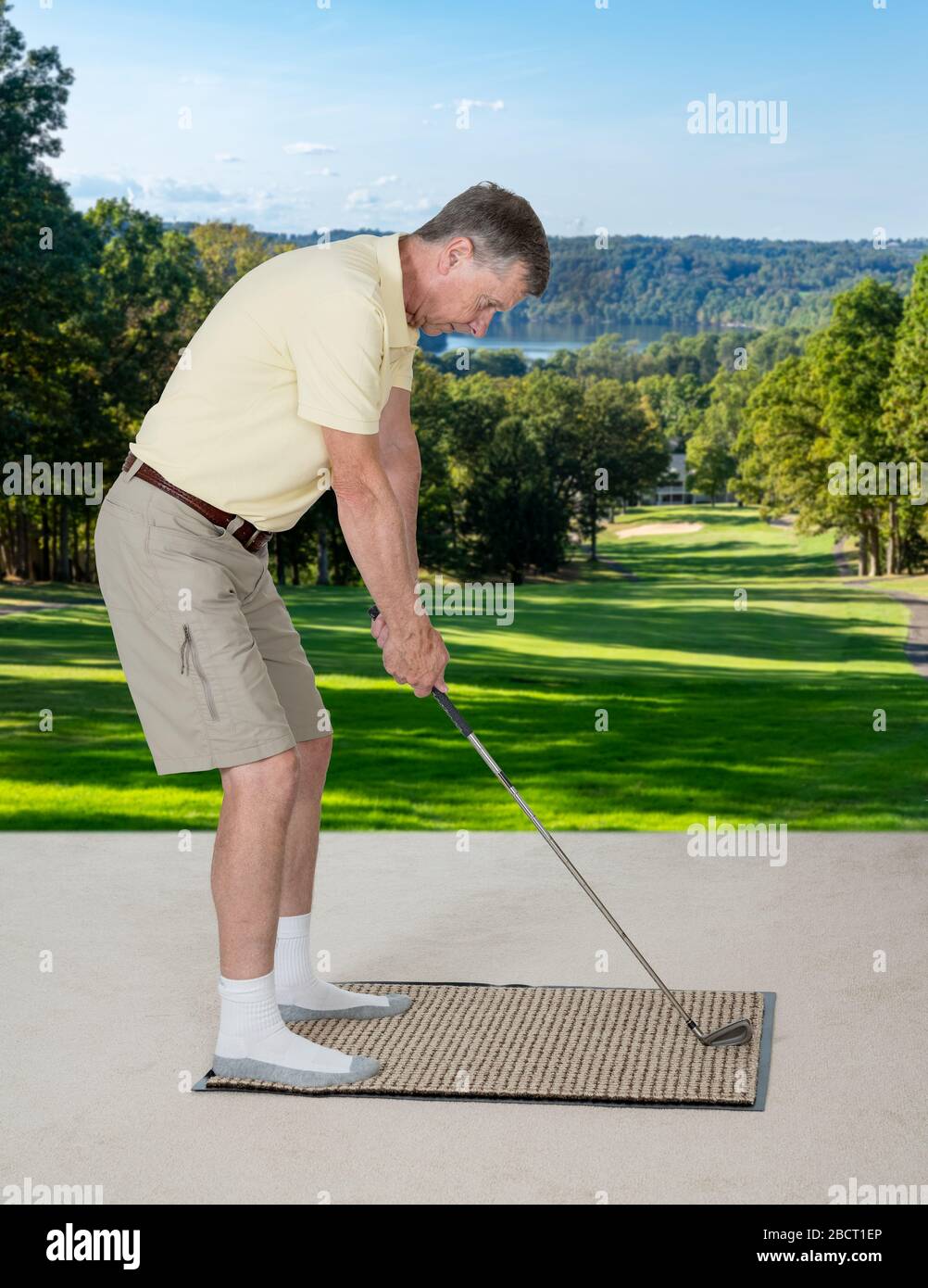 Senior caucasian man practicing his golf grip and swing on a mat in bedroom at home and imagining he was outside on a real golf course Stock Photo