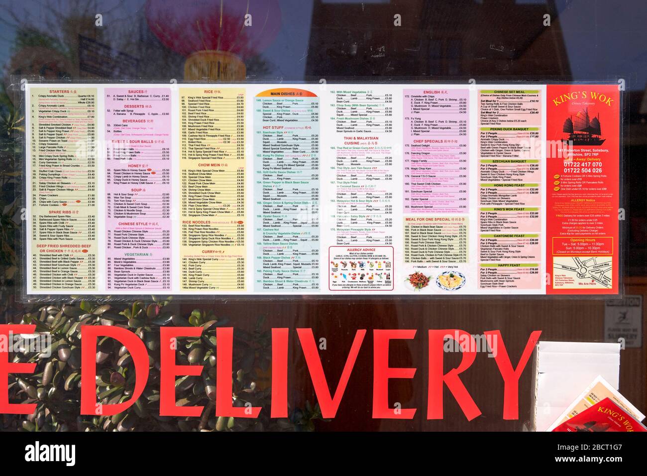 Extensive Chinese food menu and prices in the window of a takeaway with the word delivery below Stock Photo
