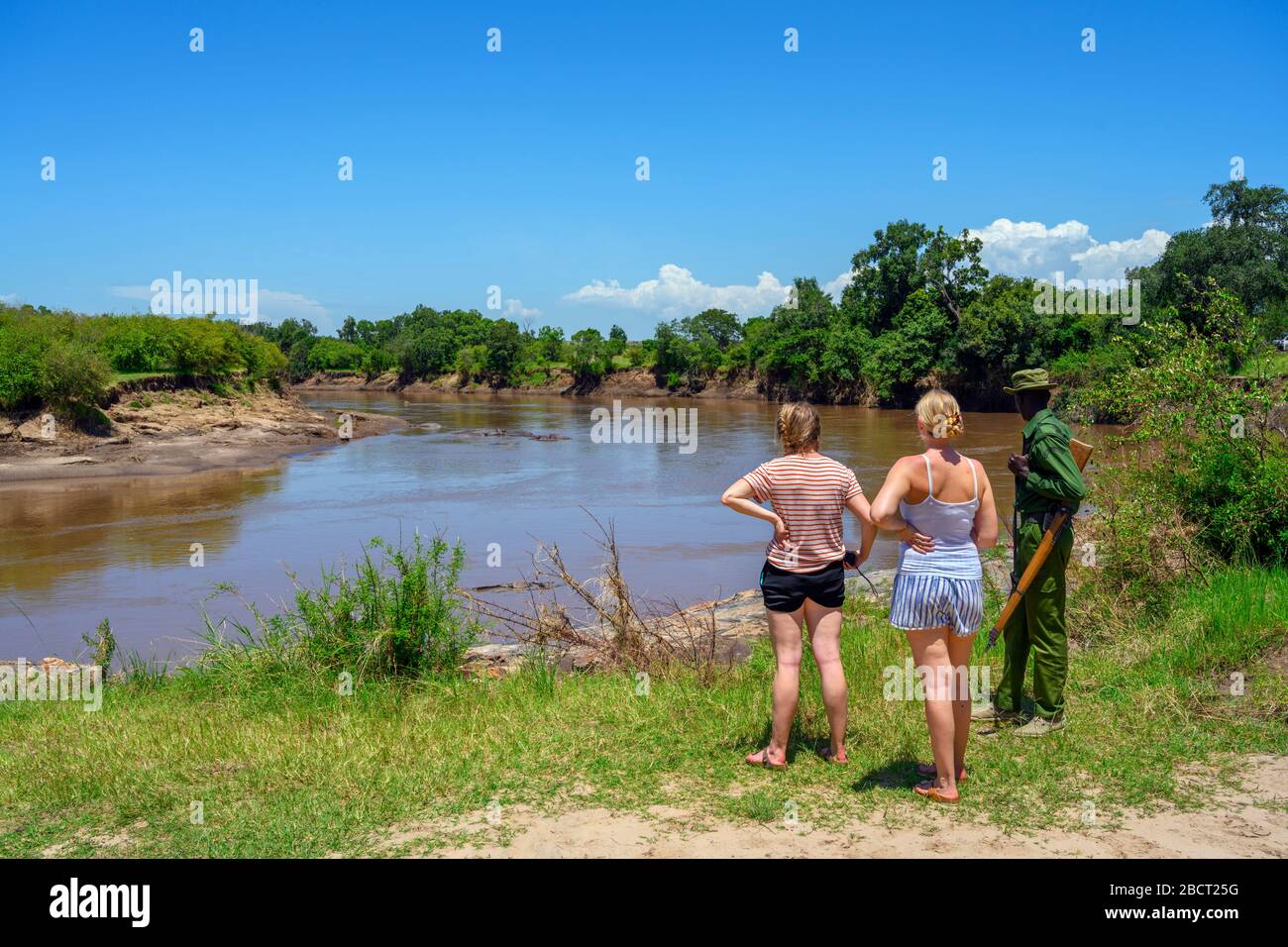 Tourists, with a park ranger, looking at hippos and crocodiles in the Mara River, Mara Triangle, Masai Mara National Reserve, Kenya, East Africa Stock Photo