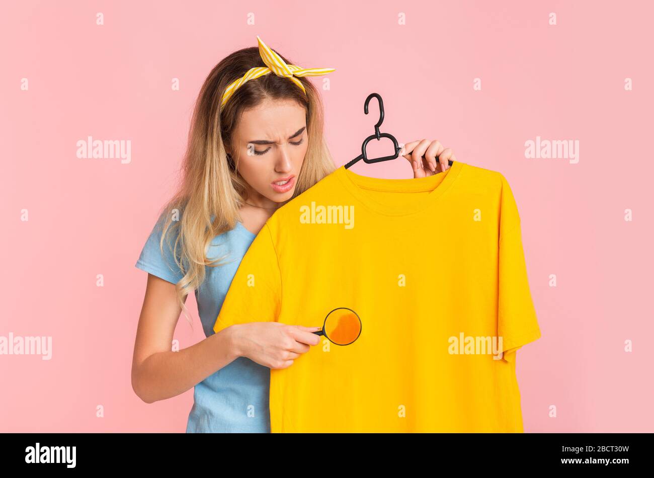 Find and remove stain on clothes. Housewife with magnifier Stock Photo