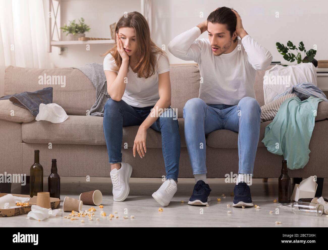 Millennial Couple Waking Up In A Messy Room After Party Stock Photo
