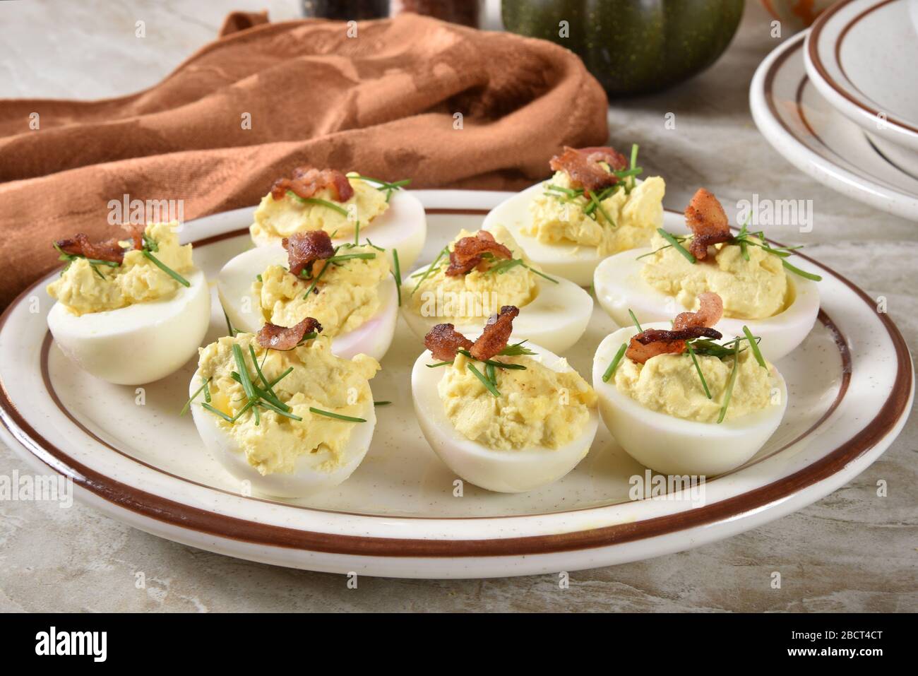 A plate of deviled eggs with chives and bacon bits Stock Photo