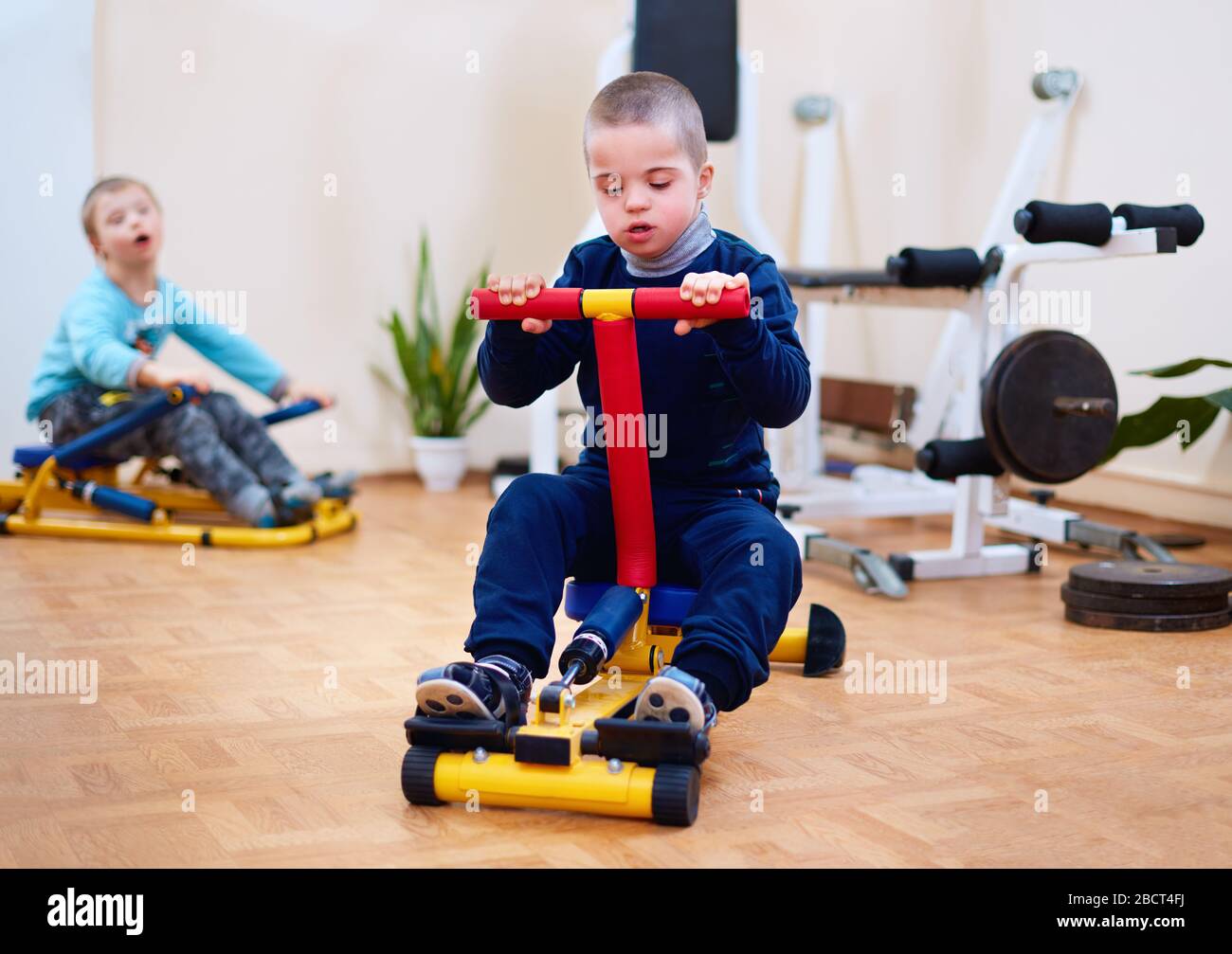 young kid with special needs exercising on inclusive sport equipment, developing muscular strength at rehabilitation center Stock Photo