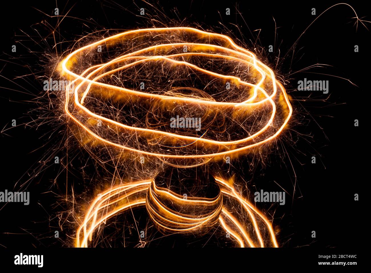 Light painting with a sparkler circling around a glass ball on a black background. Stock Photo