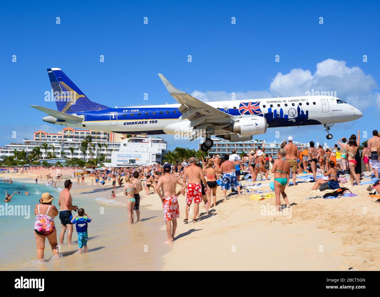 Embraer 190 (E190) extreme low approach to St. Maarten Airport over Maho Beach. ERJ-190 aircraft for flight tests. Tourist attraction in St. Martin. Stock Photo