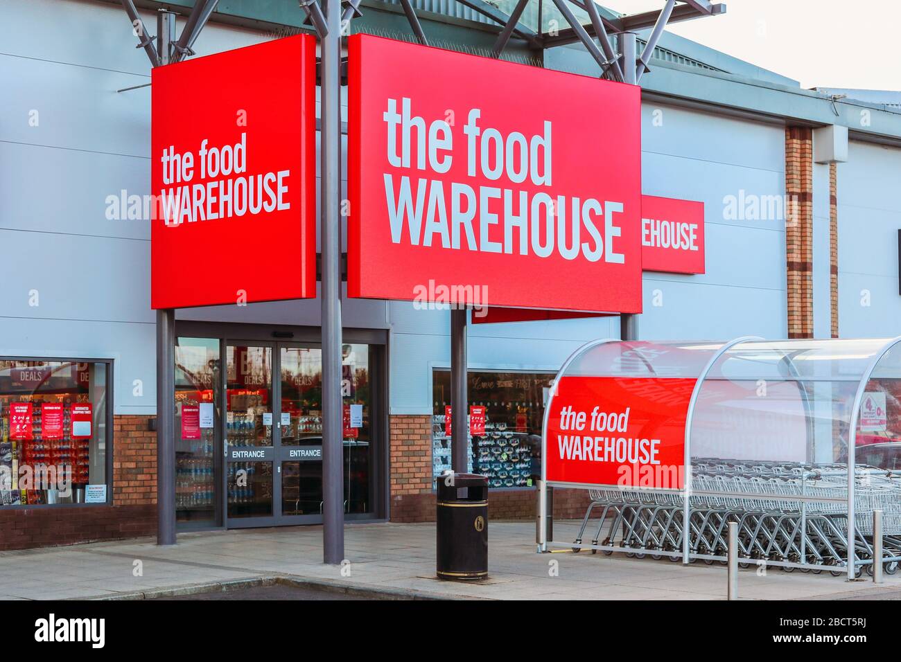 Entrance to the supermarket, the food warehouse showing the entrance and company logo on the signage and trolley park, Irvine Stock Photo
