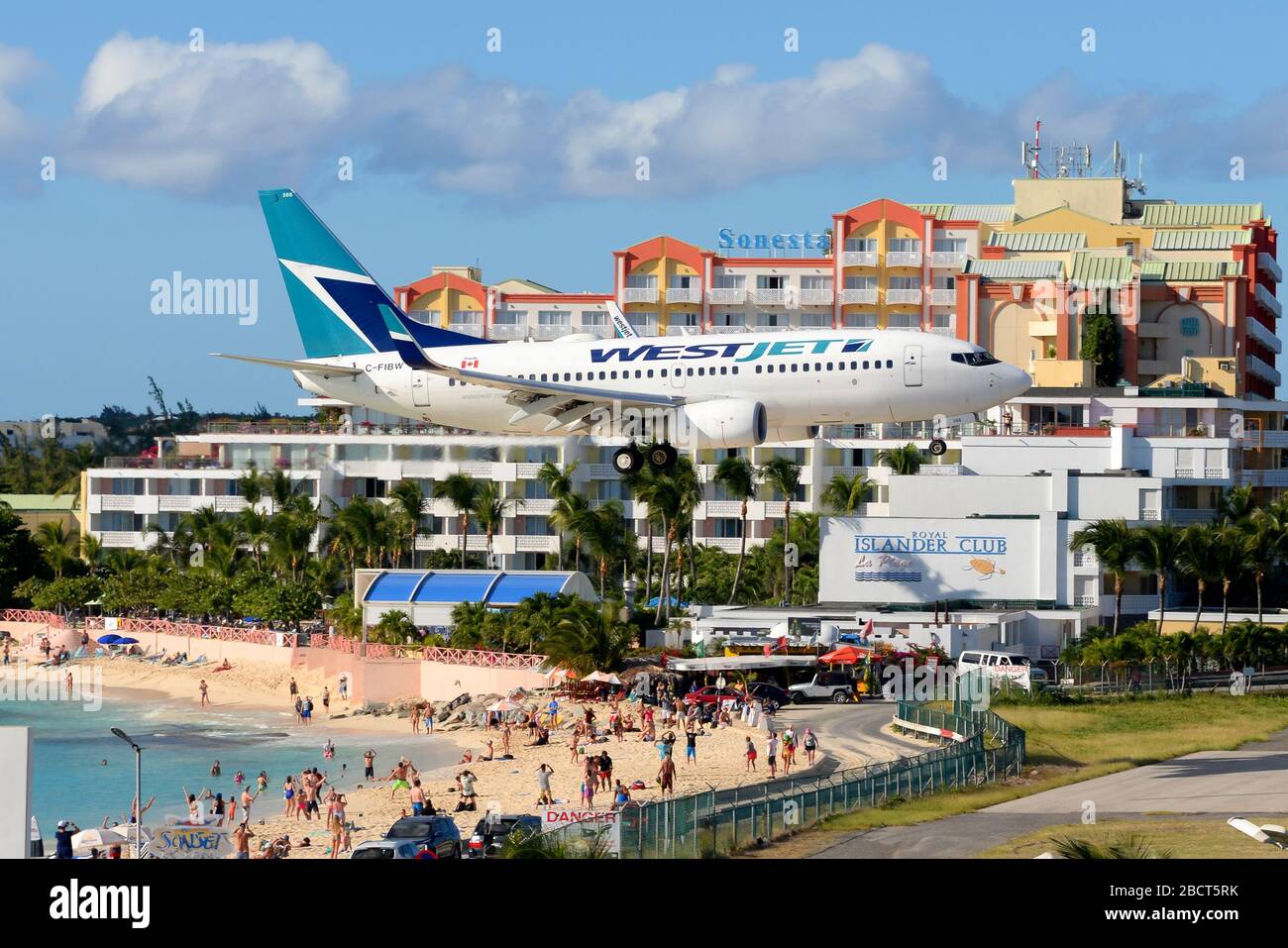 WestJet Airlines Boeing 737 passing over Maho Beach in St. Maarten. Aircraft registered as C-FIBW (Saint Maarten / Dutch Antilles). Stock Photo