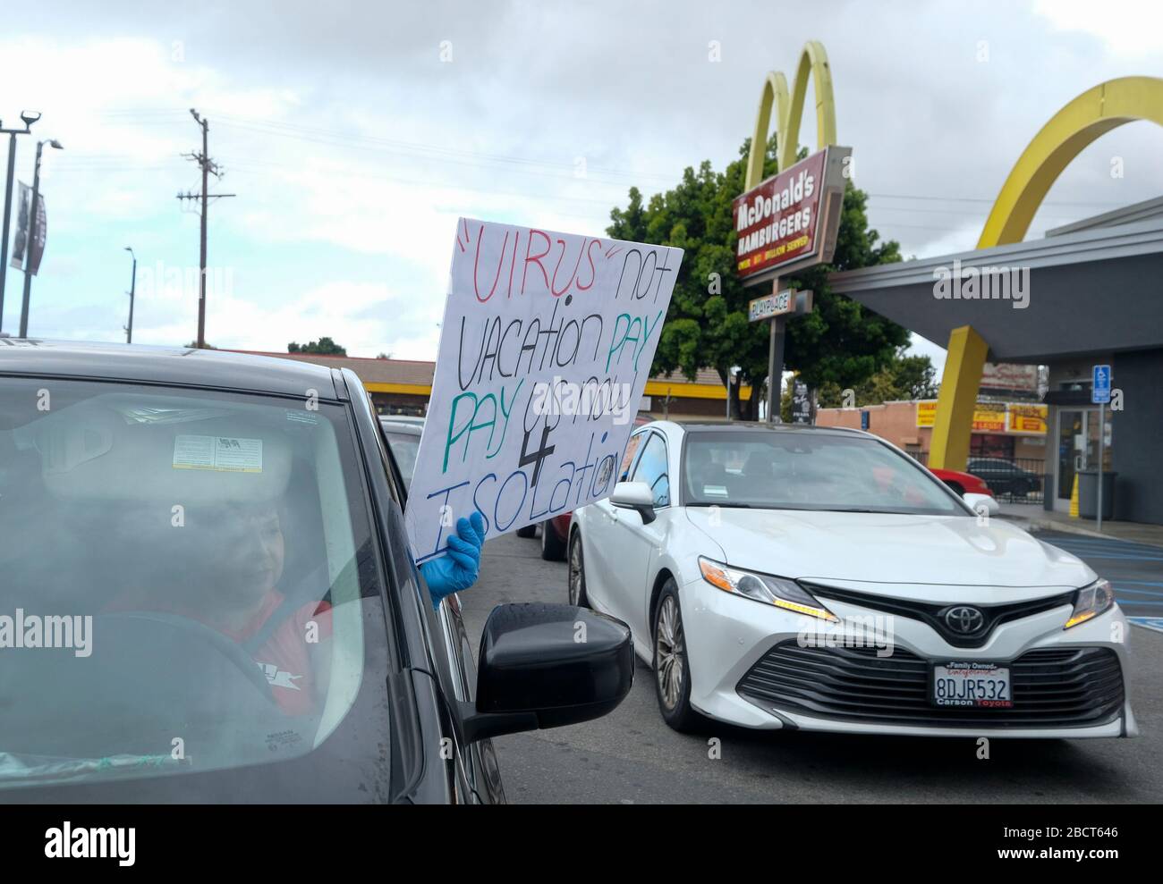 Los Angeles, California, USA. 5th Apr, 2020. A worker wearing gloves takes part in a drive-thru ''strike'' at a McDonald's restaurant on Sunday, April 5, 2020 in Los Angeles. The workers are demanding a two-week quarantine period, with full pay for a co-worker who tested positive for COVID-19. Credit: Ringo Chiu/ZUMA Wire/Alamy Live News Stock Photo