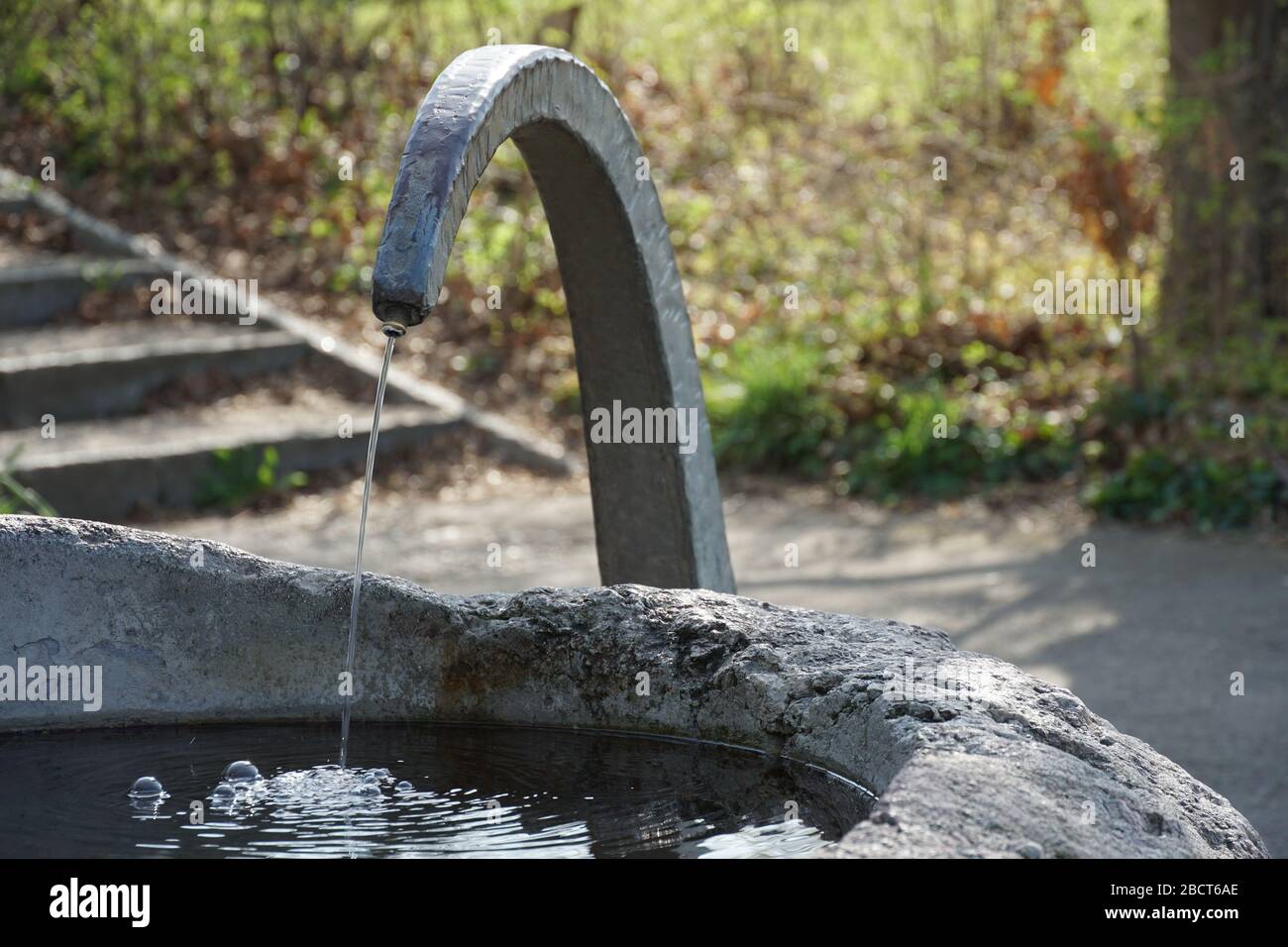A small drinking well of stone and metal, a source of drinking water accessible for free to everyone in public place Stock Photo