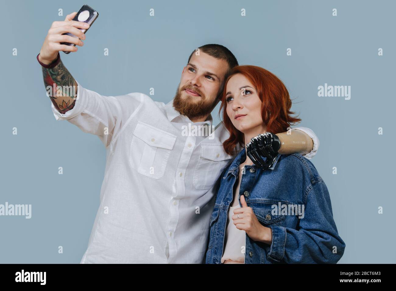 Bionic man taking selfie with a woman over blue background Stock Photo