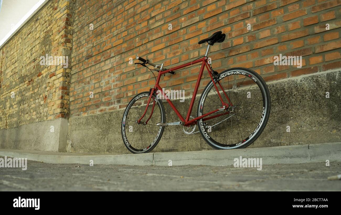 Retro styled red Singlespeed fixed gear bike leaning isolated on a brick wall Stock Photo