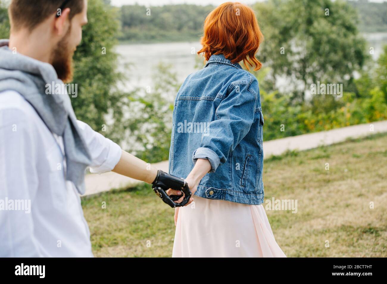Couple strolling in a park, woman pulling a man by the hand Stock Photo